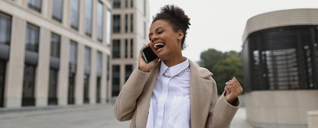 Imprenditrice afroamericana con una faccia soddisfatta e un sorriso parla su un telefono cellulare dopo