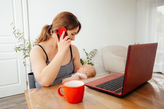 Imprenditrice che lavora a distanza tenendo il neonato addormentato