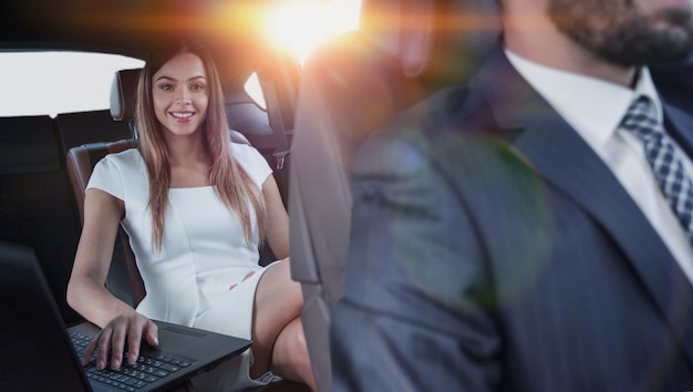 Imprenditrice che lavora durante il viaggio in ufficio in un'auto di lusso.