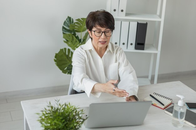 Imprenditrice che lavora in ufficio facendo videochiamata con il laptop Professionista femminile che fa videochiamata