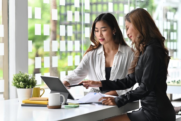 Imprenditrice che punta sul computer portatile durante la collaborazione con il collega