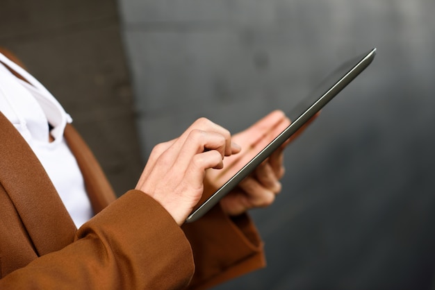 Imprenditrice con computer tablet che si leva in piedi fuori di un ufficio