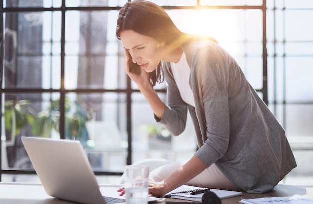 Imprenditrice con telefono in ufficio moderno a parlare