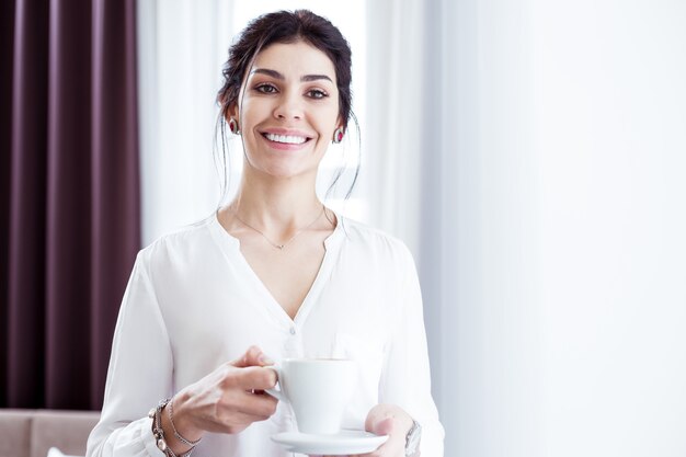 Imprenditrice di successo. Ritratto di una donna intelligente felice felice che ti sorride mentre beve il caffè