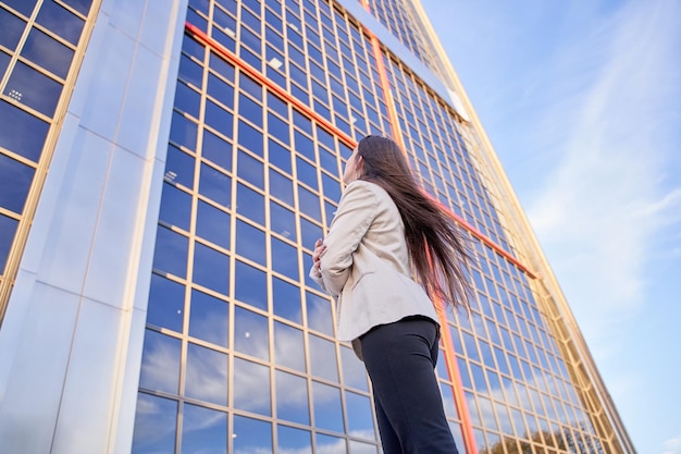 Imprenditrice guardando un edificio per uffici donna irriconoscibile con le spalle a un edificio moderno