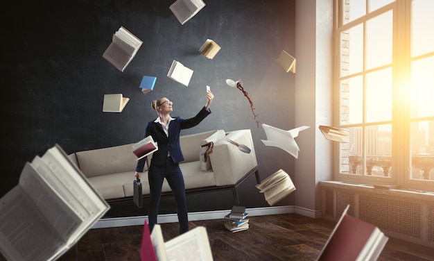 Imprenditrice in piedi e fare selfie con libri volanti tutt'intorno a lei. Tecnica mista