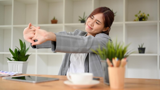 Imprenditrice o dipendente di sesso femminile che allunga le braccia dopo il lavoro rilassante nel suo posto di lavoro