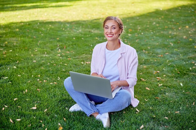 Imprenditrice seduta erba estate parco utilizzando laptop Business persone che lavorano a distanza