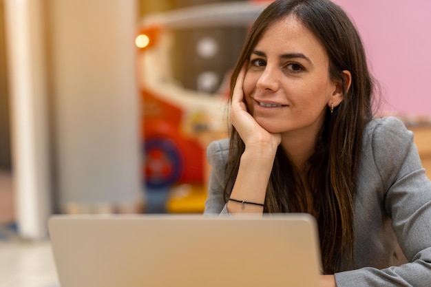 Imprenditrice sorridente con la mano al mento utilizzando il computer portatile