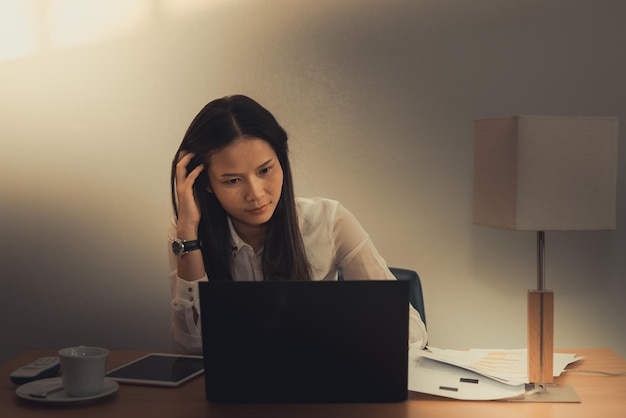 Imprenditrice stress da duro lavoro sulla scrivania in ufficio scuro tonethailand persone