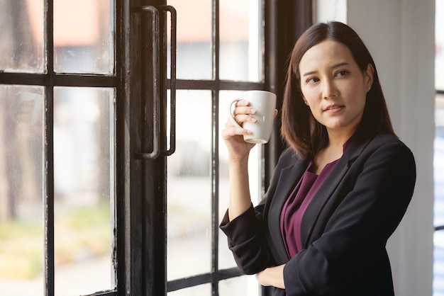 Imprenditrice tenendo la tazza di caffè in ufficio