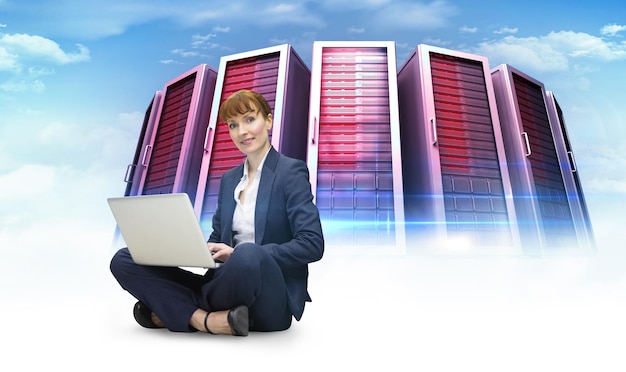 Imprenditrice utilizzando il computer portatile contro l'immagine composita delle torri del server
