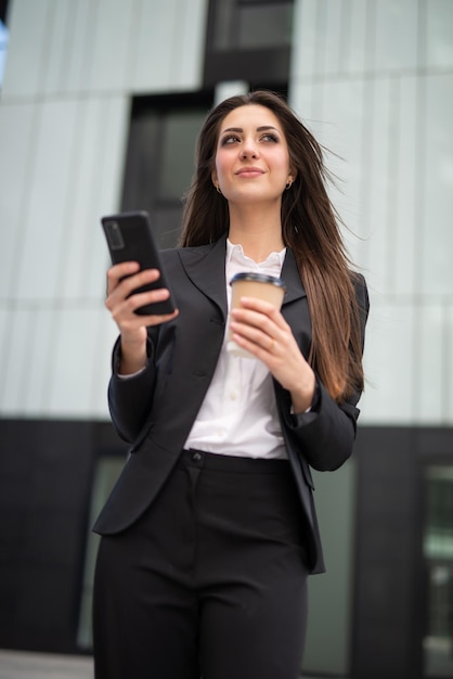 Imprenditrice utilizzando il suo smartphone in una piazza moderna della città