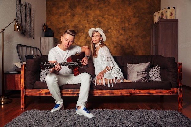 Impressionante giovane uomo e donna in abiti bianchi con la chitarra