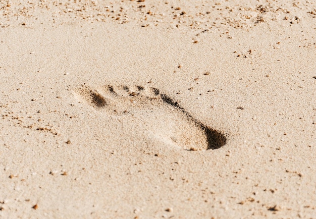 Impronta di un piede nella sabbia in primo piano sulla spiaggia