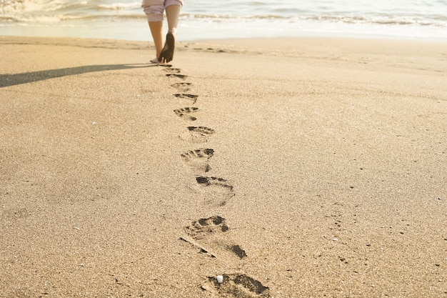 Impronte di piedi sulla sabbia della spiaggia