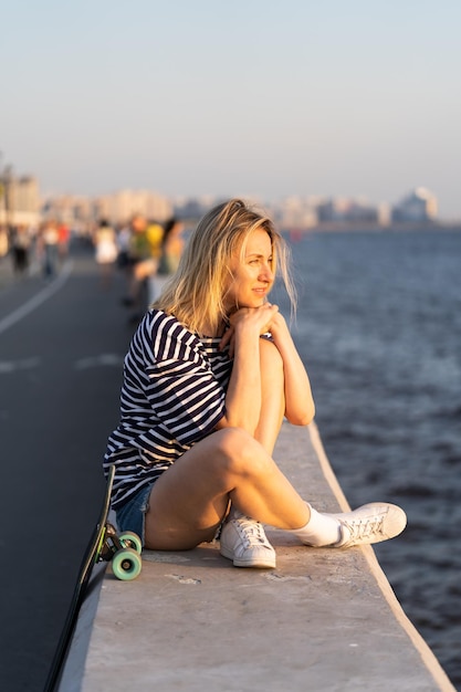 In armonia con te stesso, donna seduta da sola sulla riva del fiume, goditi il concetto di libertà del tramonto estivo