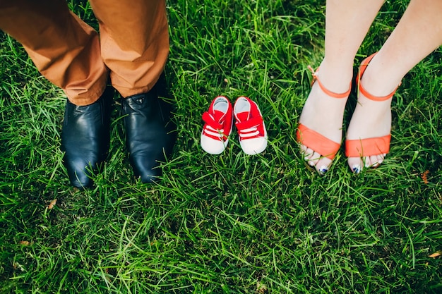 In attesa di un miracolo. scarpe per adulti e bambini. scarpe per bambini sull'erba tra le gambe dei genitori.