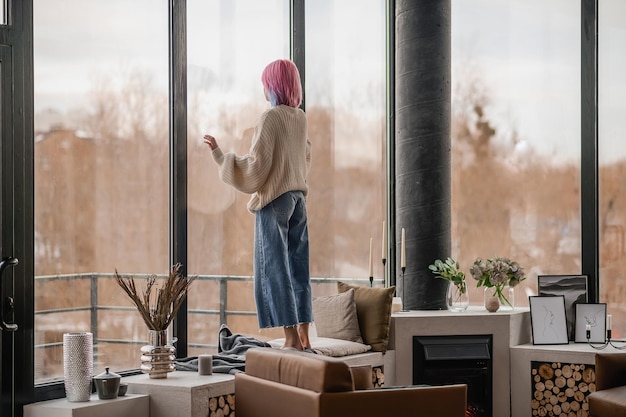 In attesa Una ragazza con i capelli rosa in piedi vicino alla finestra