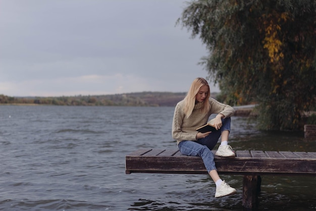 In autunno una ragazza sulla sponda del fiume legge un libro