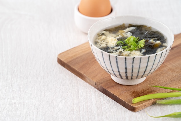 In casa deliziosa zuppa di goccia di uova di alghe marine in una ciotola sopra il fondo della tavola in legno chiaro.