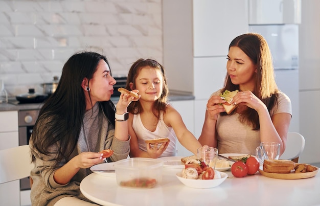 In cucina Coppia lesbica femminile con la piccola figlia che trascorrono del tempo insieme a casa