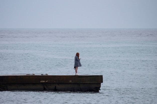 In estate, una ragazza con i capelli lunghi si trova sul molo, guardando la telecamera.