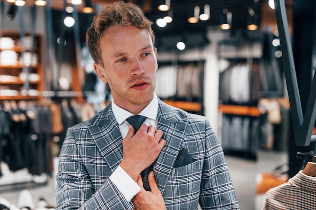 In giacca con cravatta Giovane ragazzo in un negozio moderno con vestiti nuovi Abbigliamento elegante e costoso per gli uomini