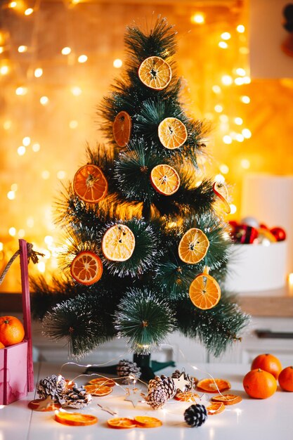 In inverno, l'albero è decorato con arance essiccate all'esterno, rami verdi su uno sfondo sfocato e bokeh giallo-oro. Decorazioni festive in stile ecologico. Buon Natale.