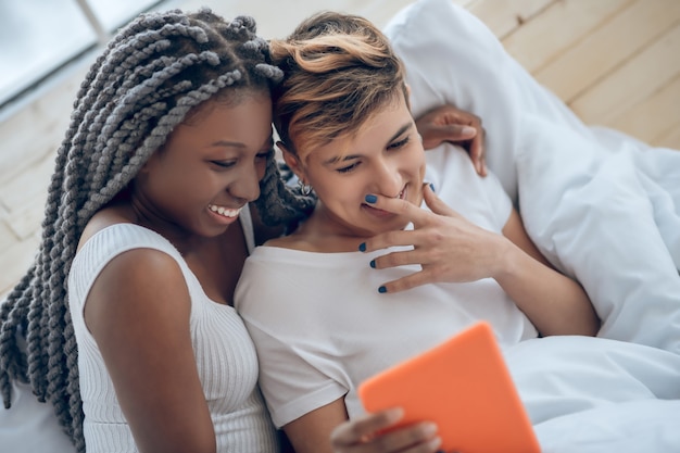 In linea. Due ragazze sdraiate a letto e stanno guardando qualcosa su Internet