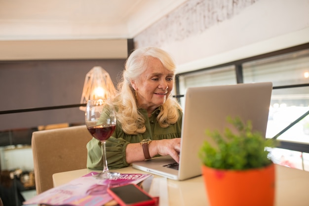 In linea. Elegante donna anziana che chatta online e si sente coinvolta