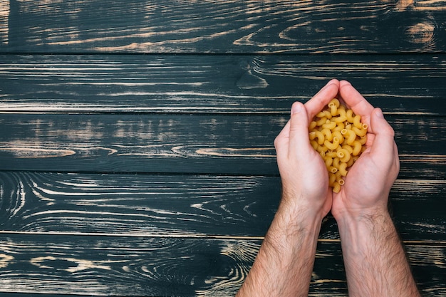 In mani maschili pasta su fondo di legno nero