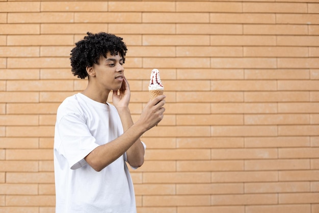 In piedi di lato un ragazzo americano premuroso con in mano un gelato con marmellata rossa