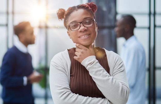 È in piedi in un ufficio moderno con i suoi colleghi sullo sfondo