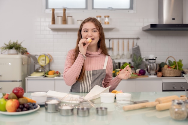 In piedi su un divano a casa, una ragazza felice mangia un biscotto dietetico.