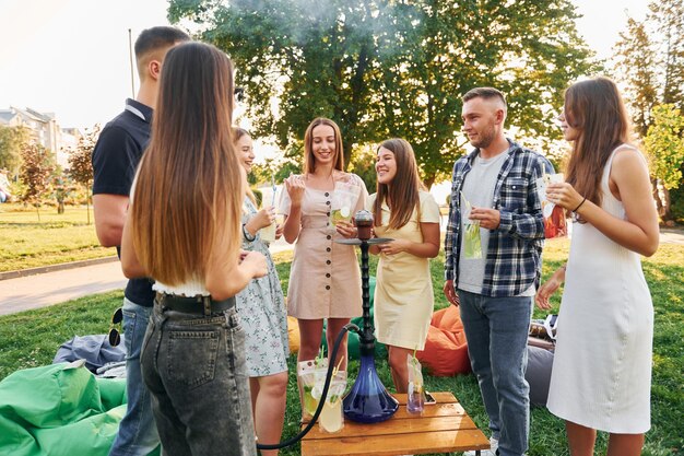 In piedi vicino al narghilè Un gruppo di giovani organizza una festa nel parco durante il giorno d'estate