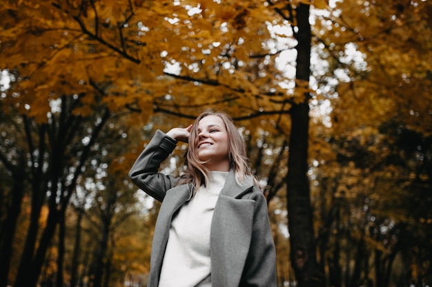 In posa per un servizio fotografico nella natura Ritratto autunnale di una giovane ragazza in un parco autunnale con un cappotto grigio