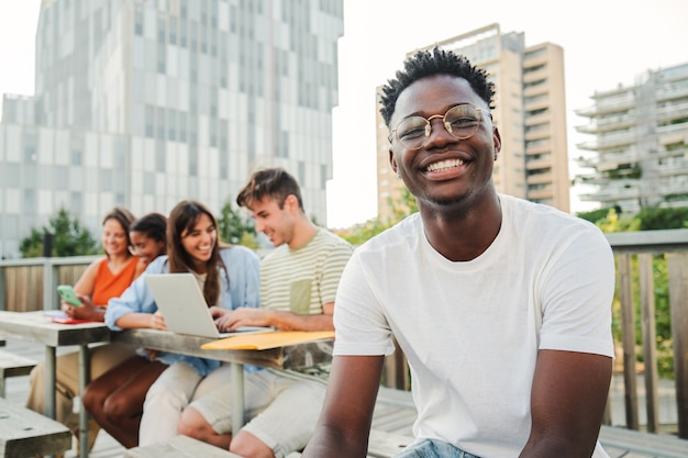 In primo piano un giovane studente afroamericano allegro e sorridente con una fotocamera che guarda positivamente