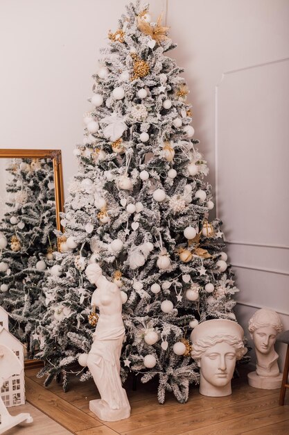 In un'accogliente stanza luminosa c'è un albero di Natale verde decorato con inrushki leggeri con regali