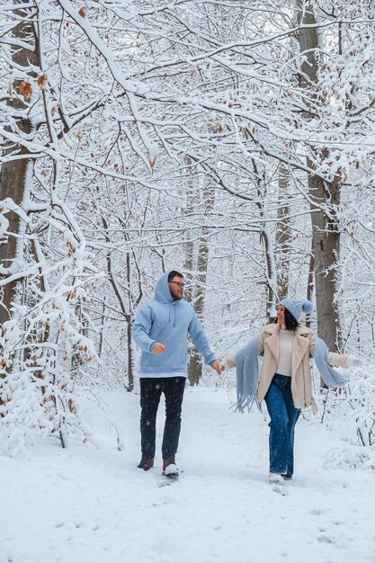 In un bosco pieno di neve invernale una coppia innamorata corre