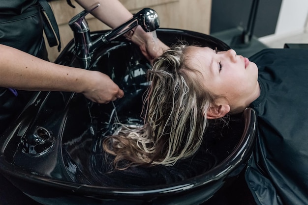 In un parrucchiere d'élite, la bella giovane donna si lava la testa su una sedia speciale Il concetto di lavare la testa in un salone di bellezza