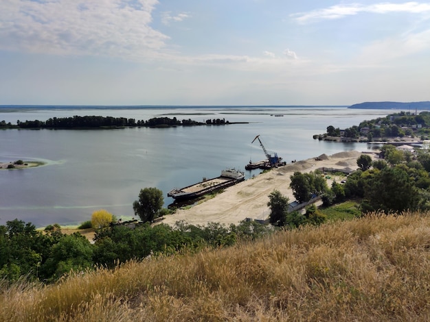 In un piccolo porto una gru carica una chiatta di sabbia Vista dall'alto con uno splendido paesaggio