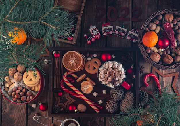 In un vassoio di legno c'è una tazza rossa con marshmallow e gli attributi di Capodanno