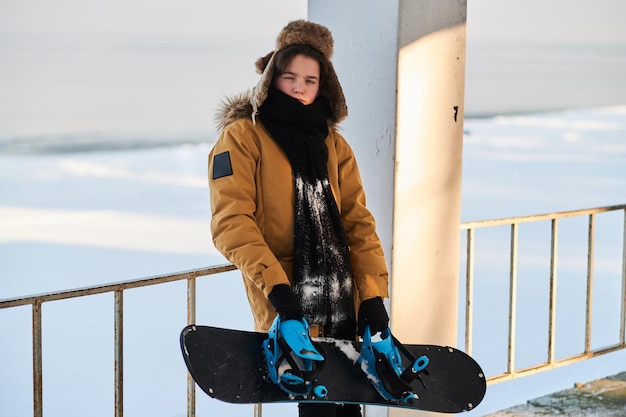 In una luminosa giornata di sole, il giovane snowbordist posa per il fotografo con il suo snowboard.