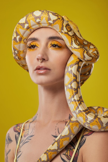 In uno stato d'animo d'oro. Inquadratura di una giovane donna in posa con un serpente in testa su uno sfondo giallo.