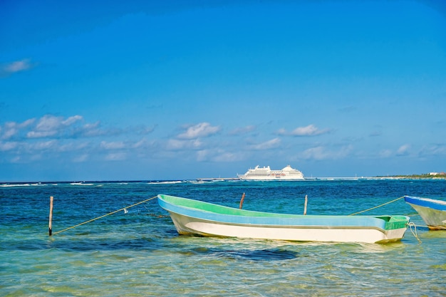 In viaggio. barca sulla spiaggia in mare limpido o acqua oceanica e nave da crociera bianca in giornata di sole sul cielo blu in Costa Maya, Messico. Vacanze estive