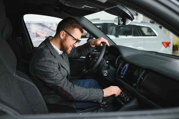 In visita alla concessionaria di automobili Bell'uomo barbuto sta accarezzando la sua nuova auto e sorridendo