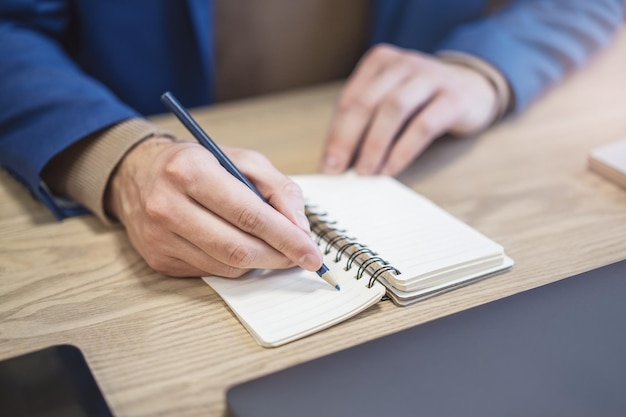 In vista ravvicinata la mano di un uomo che scrive appunti in un blocco note su uno sfondo nebbioso