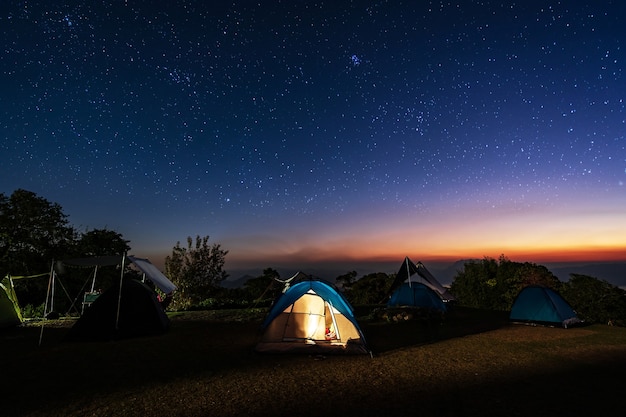 Incandescente tenda da campeggio sulla montagna sotto un bellissimo cielo stellato di notte, stile di vita di viaggio