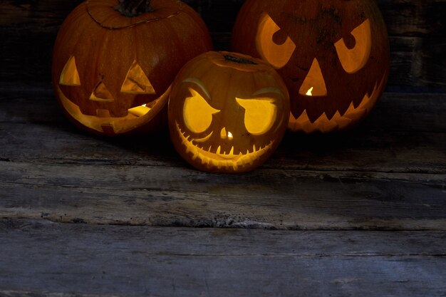 Incandescente teste di zucca di halloween jack lanterna tre zucche intagliate con candele accese all'interno felice...